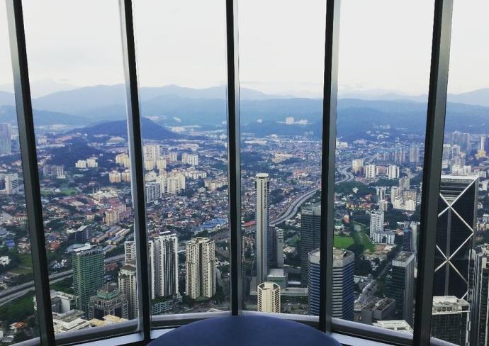 Interior view from Petronas Twin Towers observation deck showing floor-to-ceiling windows overlooking Kuala Lumpur cityscape